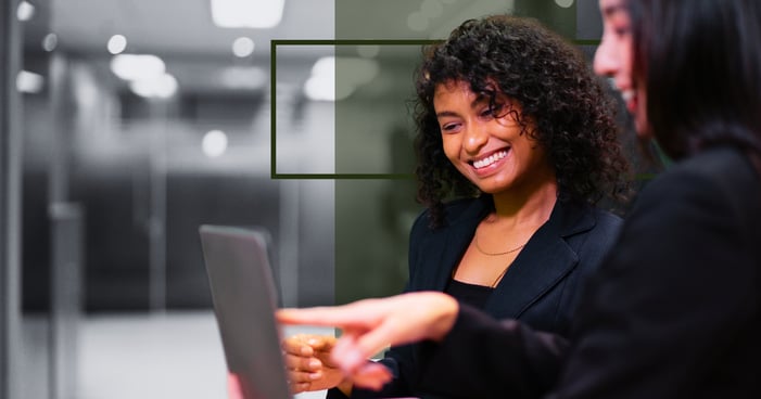 Two professionals look at a laptop together with green design elements in the background.