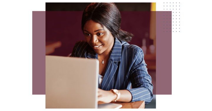 woman in office working on a laptop with a smile on her face