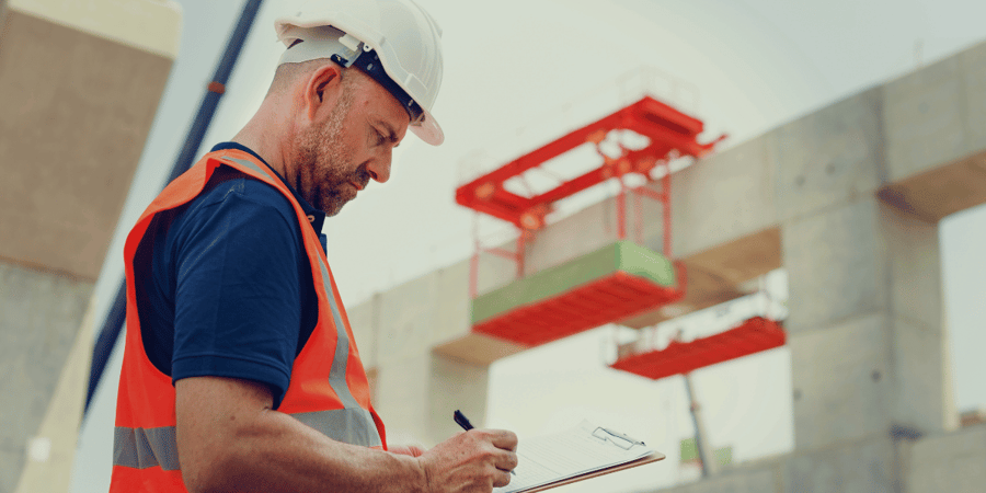 Foreman filling out sheet on a clipboard on construction site