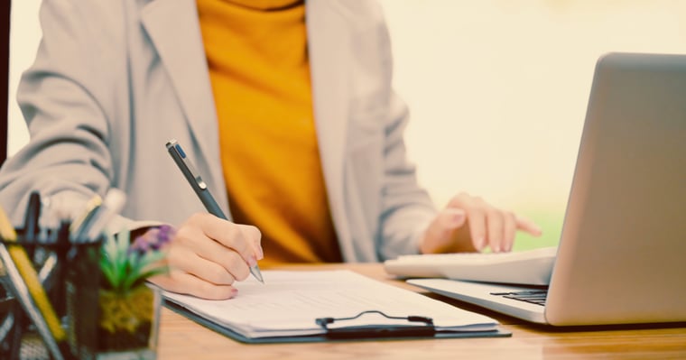 HR professional fills out paperwork by laptop