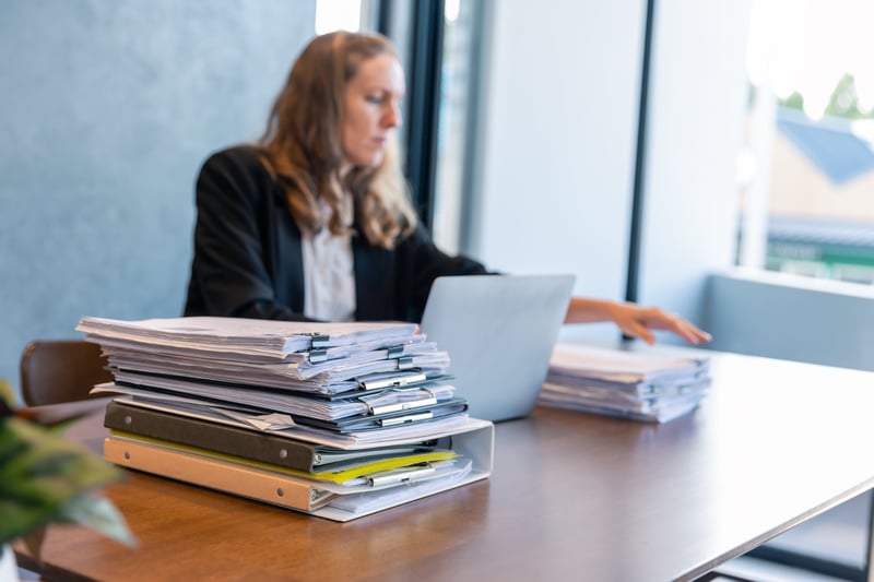 businesswoman-working-with-stacks-of-documents-2024-12-07-23-46-21-utc