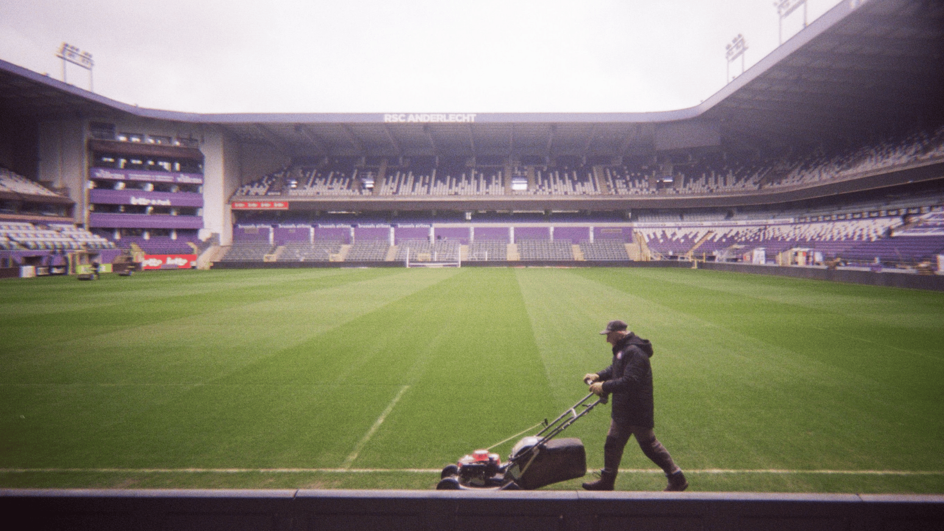 sporting venue part-time worker mowing grass