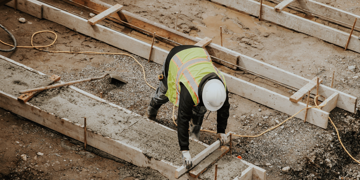 construction worker placing concrete at a site construction worker placing concrete at a site