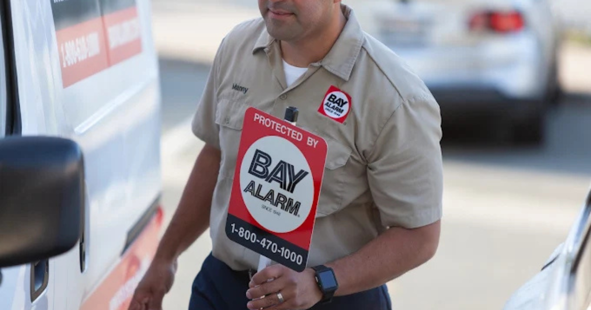 Worker holds a bay alarm sign while getting into a van