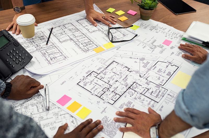 construction plans on a table with people around it construction plans on a table with people around it