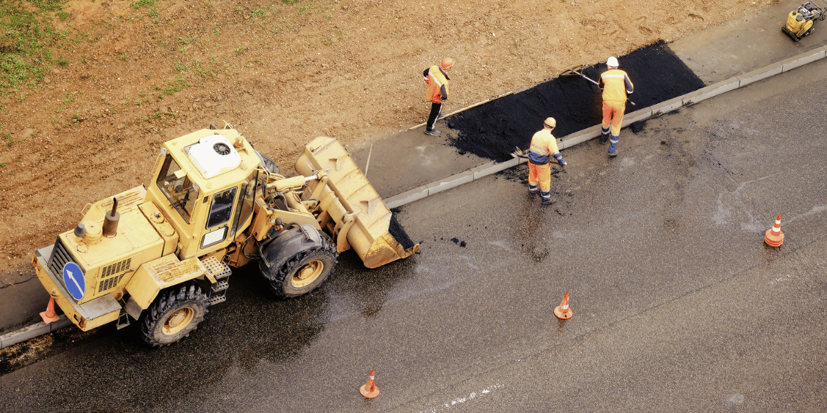 three construction workers and heavy equipment road construction three construction workers and heavy equipment road construction