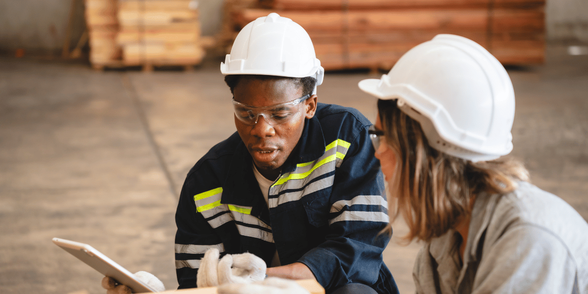 Apprentice and supervisor reviewing construction plans on a job site.
