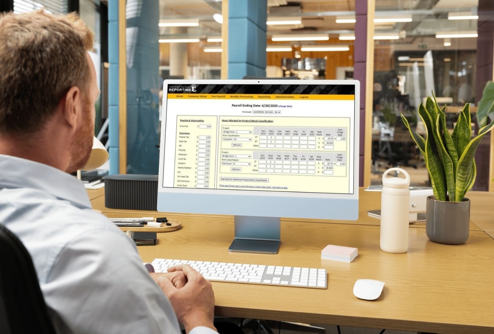 man looks at the certified payroll reporting dashboard in his office on his computer. man looks at the certified payroll reporting dashboard in his office on his computer.