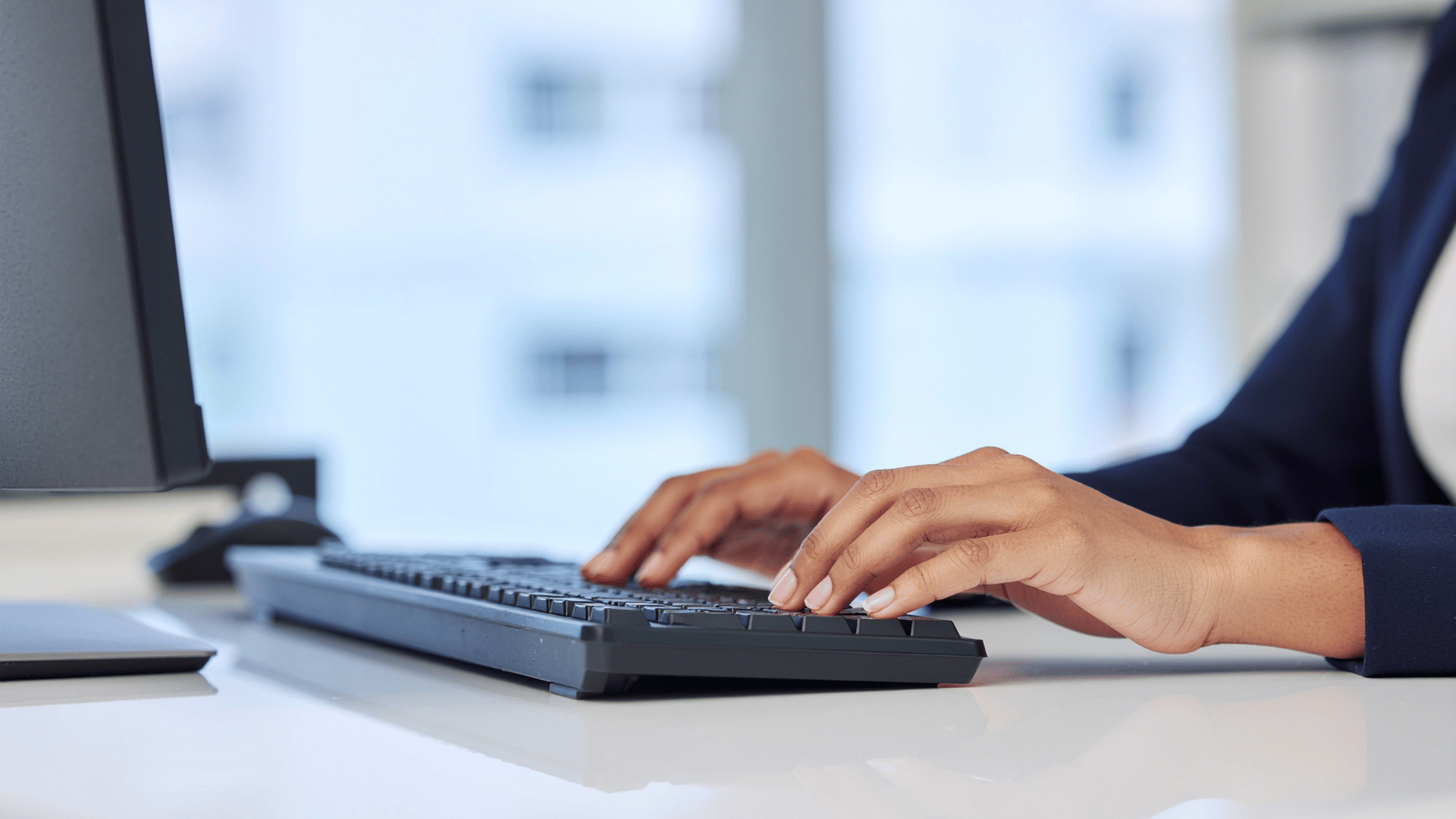 personal in business wear typing on a keyboard